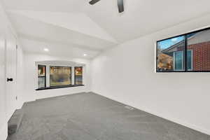 Carpeted empty room featuring ceiling fan and lofted ceiling