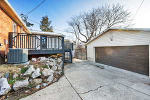 View of property exterior with an outdoor structure, a garage, central air condition unit, and a wooden deck