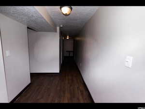 Hall with dark wood-type flooring and a textured ceiling