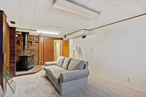 Carpeted living room with a wood stove and wooden walls