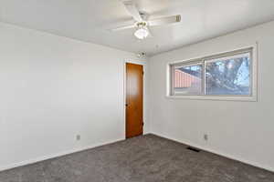 Carpeted spare room featuring ceiling fan