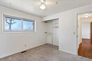 Unfurnished bedroom featuring ceiling fan, a closet, and light colored carpet