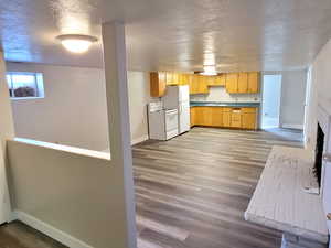 Kitchen with light wood-type flooring, a textured ceiling, white appliances, sink, and light brown cabinets