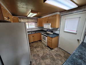 Kitchen with decorative backsplash, white appliances, and sink