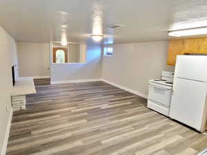 Kitchen featuring white appliances, a textured ceiling, and light hardwood / wood-style flooring