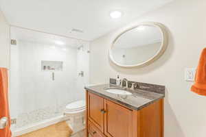 Bathroom featuring an enclosed shower, vanity, and toilet