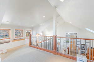 Corridor with light colored carpet and lofted ceiling with skylight