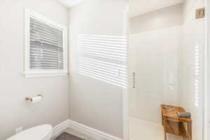 Bathroom featuring tile patterned floors, toilet, and a shower with shower door