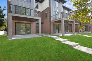 Rear view of house with a patio, a balcony, and a lawn