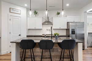 Kitchen featuring a center island with sink, white cabinetry, and light hardwood / wood-style flooring