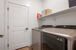 Laundry room with light hardwood / wood-style floors and washing machine and dryer