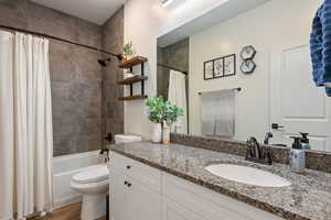 Full bathroom with hardwood / wood-style flooring, vanity, toilet, and shower / bath combo with shower curtain