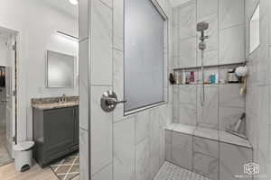 Bathroom with hardwood / wood-style floors, vanity, and tiled shower