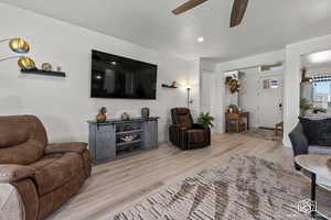 Living room with ceiling fan and light hardwood / wood-style flooring