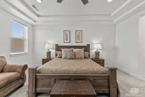 Carpeted bedroom featuring a raised ceiling and ceiling fan