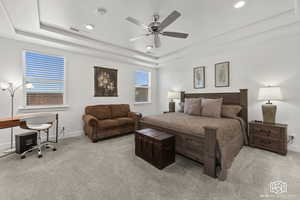 Carpeted bedroom with ceiling fan and a tray ceiling