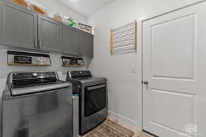 Clothes washing area featuring cabinets, light wood-type flooring, and separate washer and dryer