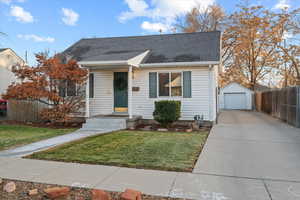 Bungalow-style house with a garage, an outbuilding, and a front yard