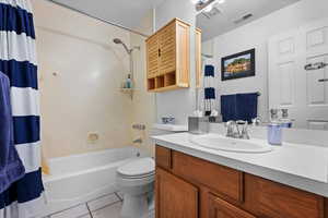 Full bathroom with tile patterned flooring, vanity, shower / bath combo, and toilet