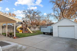 View of patio / terrace featuring an outdoor structure, a garage, and a playground