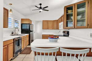 Kitchen with stainless steel appliances, sink, decorative light fixtures, lofted ceiling, and a breakfast bar area