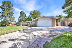 Ranch-style house featuring a shed, a front lawn, and a garage