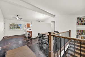 Interior space with vaulted ceiling with beams and dark hardwood / wood-style flooring