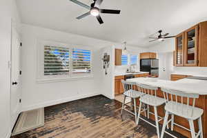 Kitchen featuring appliances with stainless steel finishes, dark hardwood / wood-style flooring, ceiling fan, sink, and a breakfast bar area