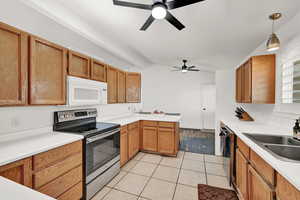 Kitchen featuring lofted ceiling with beams, sink, hanging light fixtures, light tile patterned floors, and stainless steel appliances