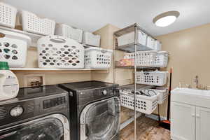 Clothes washing area with washer and dryer, cabinets, and sink