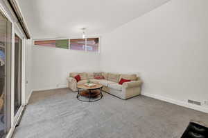 Unfurnished living room with light carpet and vaulted ceiling