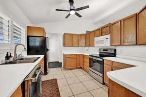 Kitchen with lofted ceiling, sink, ceiling fan, light tile patterned flooring, and stainless steel appliances