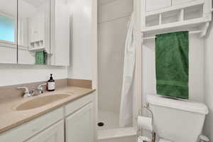 Bathroom featuring curtained shower, vanity, and toilet