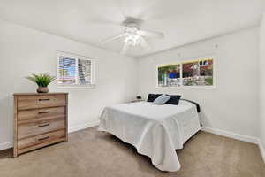 Bedroom featuring ceiling fan, light colored carpet, and multiple windows