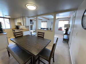 Carpeted dining area with beam ceiling and sink