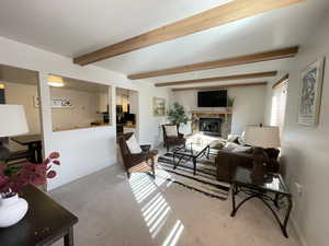 Carpeted living room with beam ceiling and a fireplace