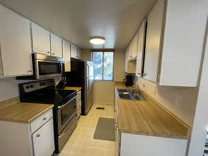 Kitchen featuring sink, white cabinetry, and stainless steel appliances