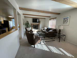 Living room with beam ceiling, a wealth of natural light, and a fireplace