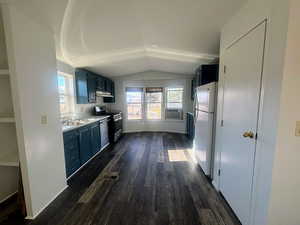 Kitchen with a wealth of natural light, dark hardwood / wood-style floors, lofted ceiling, and appliances with stainless steel finishes