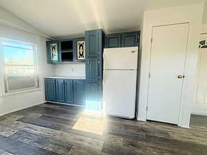 Kitchen featuring white fridge, blue cabinets, and dark wood-type flooring