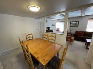 Dining space featuring carpet and beam ceiling