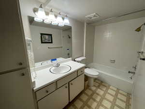 Full bathroom with vanity, tiled shower / bath combo, and toilet