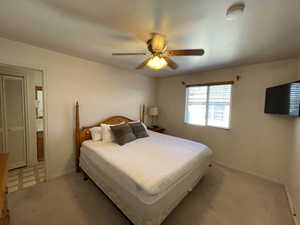 Bedroom with ceiling fan, a closet, and light colored carpet