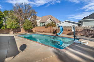 View of pool featuring a diving board, a patio, and a water slide