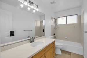 Full bathroom with vanity, tiled shower / bath combo, and toilet