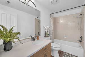 Full bathroom with a textured ceiling, toilet, shower / bath combo with shower curtain, vanity, and hardwood / wood-style flooring