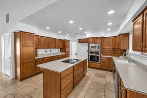 Kitchen with sink, a center island, light tile patterned floors, and appliances with stainless steel finishes