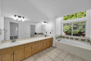 Bathroom featuring tile patterned flooring, vanity, a relaxing tiled tub, and vaulted ceiling