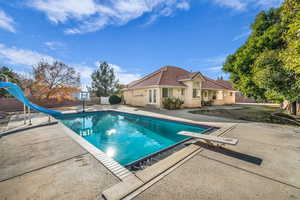 View of swimming pool with a diving board, a water slide, and a patio