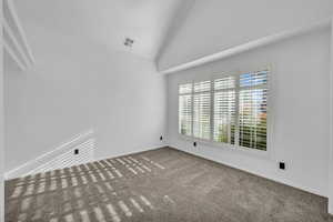 Unfurnished room with carpet floors and lofted ceiling